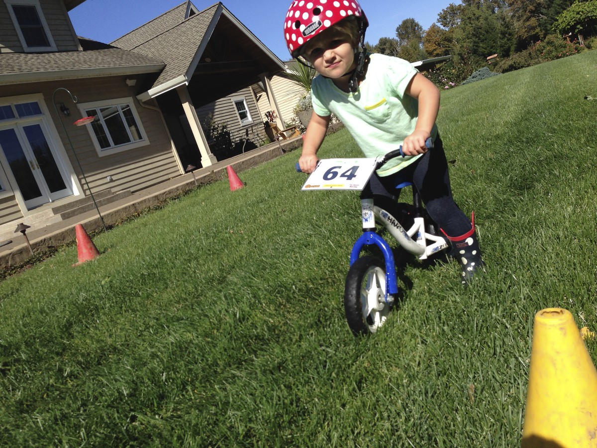 Preschooler on a scoot bike with a serious face on a lawn at a kiddie kross race