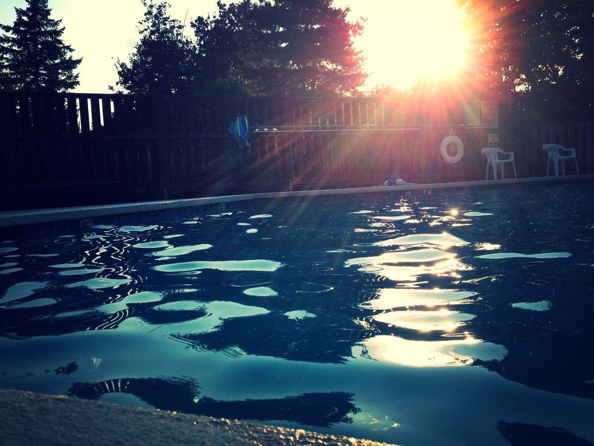 low perspective photo of a small swimming pool with no one in it, taken at sunset on the last day of summer