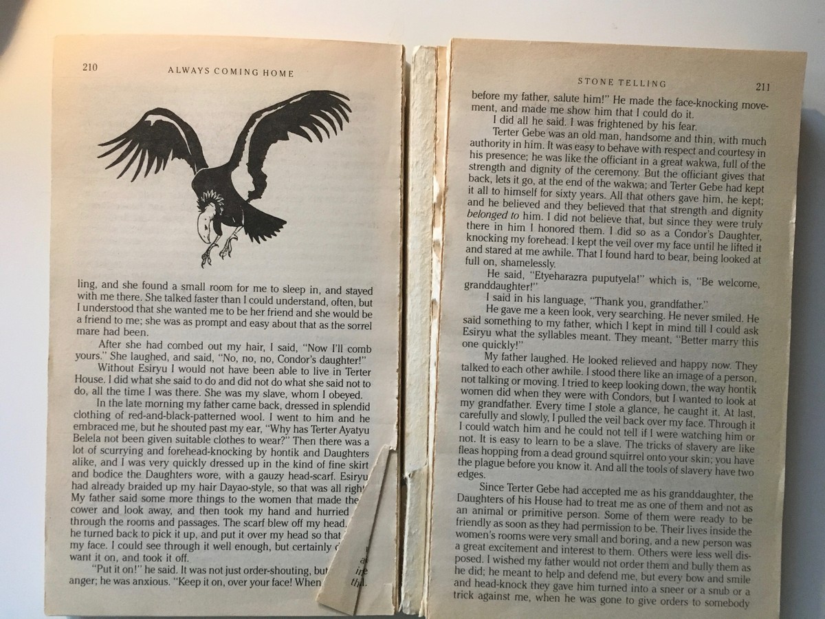 Closeup of a paperback copy of ALWAYS COMING HOME, split open to page 210, with a line drawing of a condor on one page