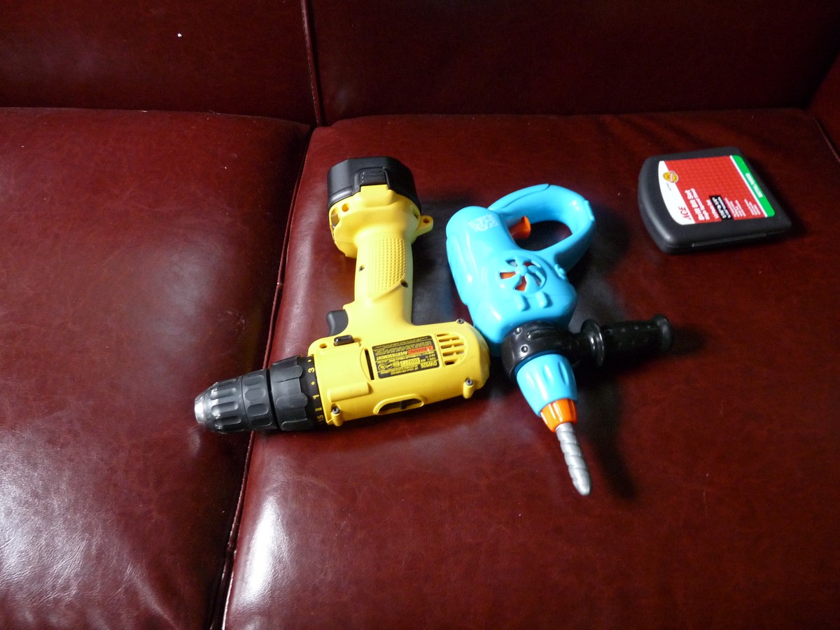 Two electric drills on the couch, one is a toy