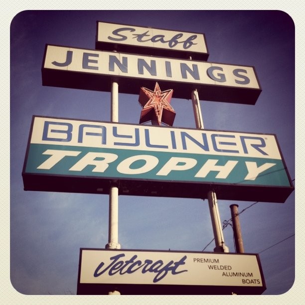 Photo of the old (1960s era) sign: “Staff Jennings / Bayliner Trophy / Jetcraft.” Photo manipulated to resemble a faded Polaroid from the 1970s