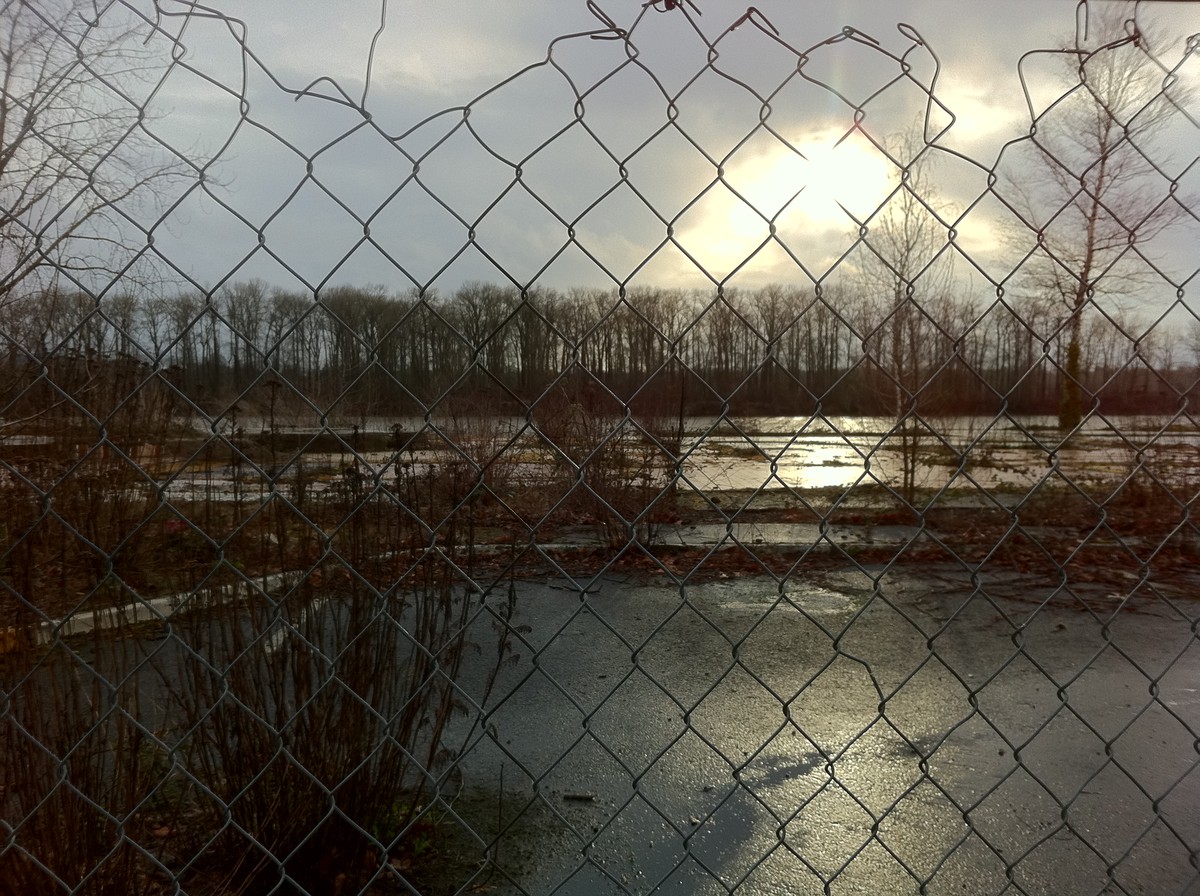 Ruins of Tequila Willies at sunrise on a rainy day, shot through a chainlink fence