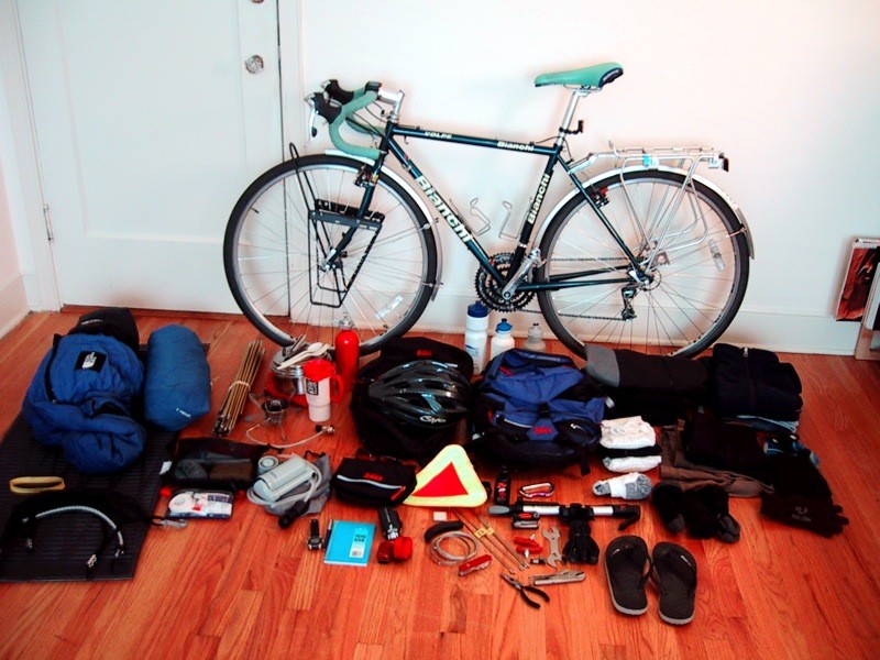 Touring bicycle and all its associated gear. Packs, sleeping bag, tent, tools, clothes, helmet, etc. Spread out on the floor in a tiny apartment