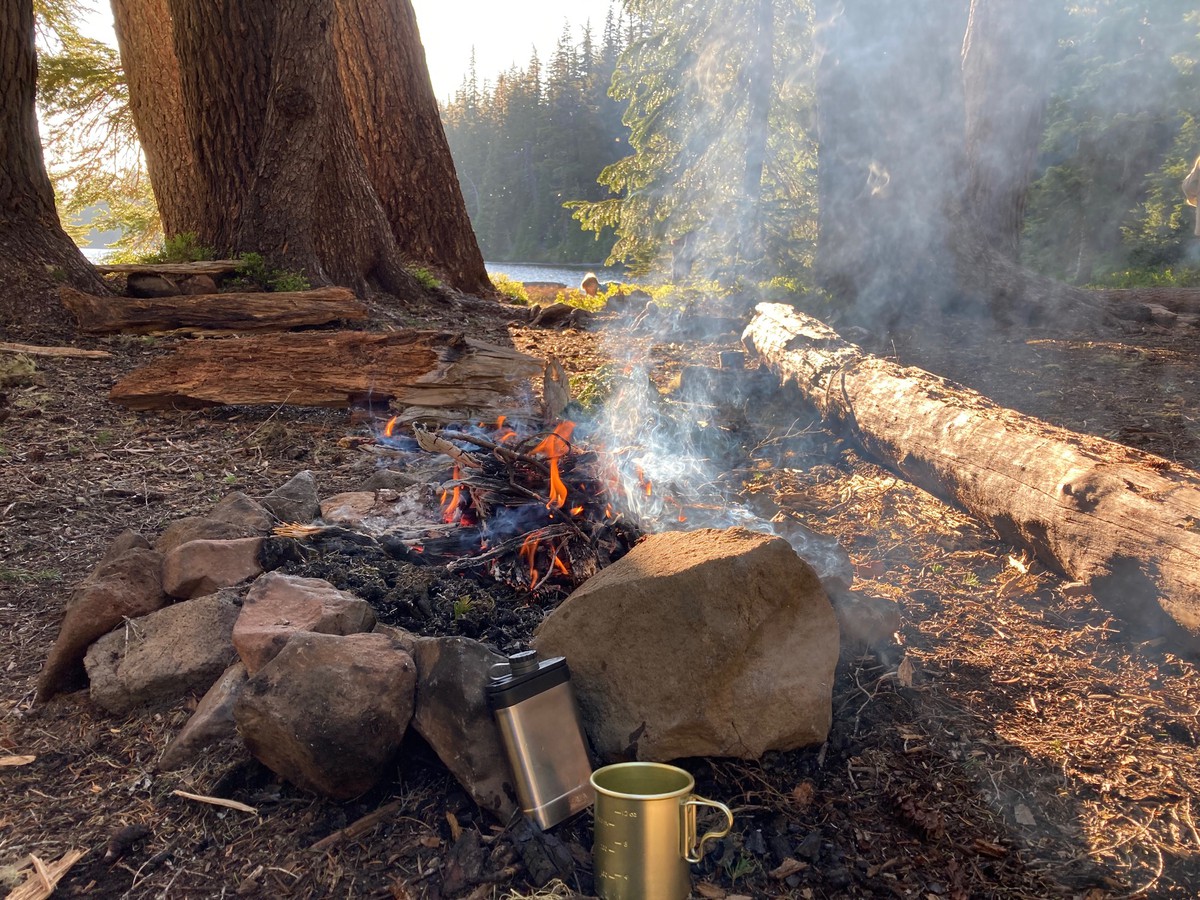 A flask of whiskey next to a campfire