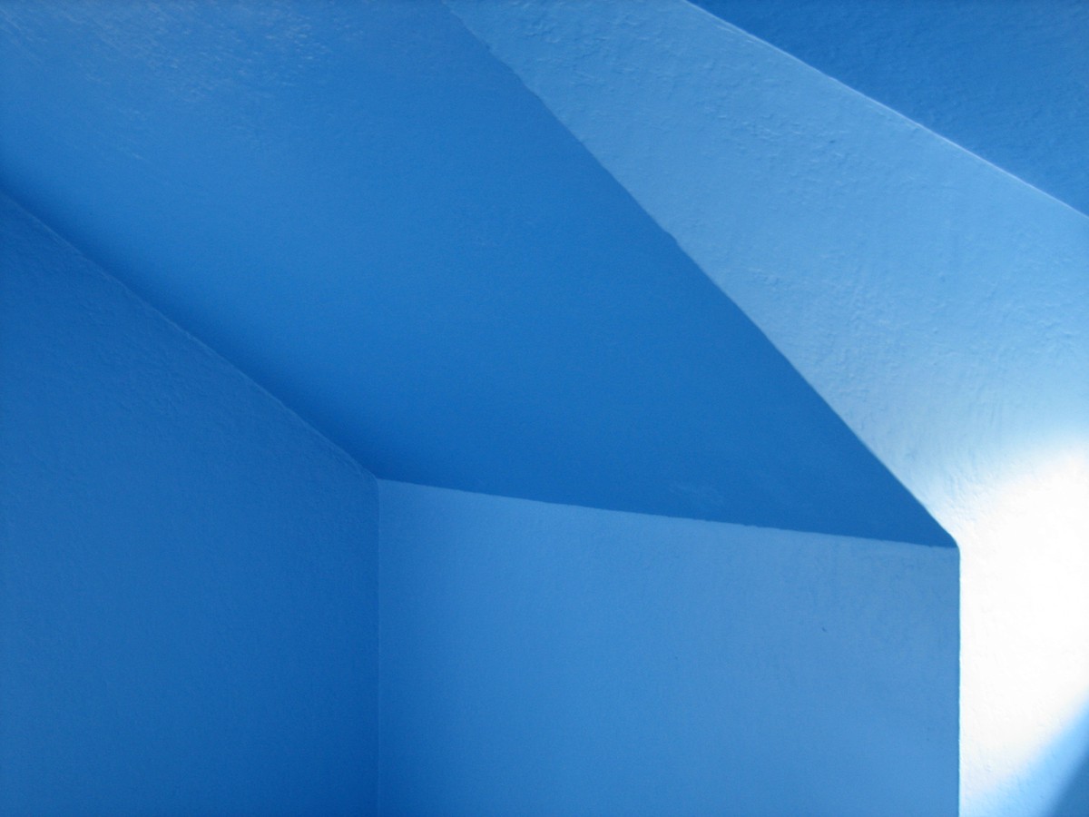 Abstractly composed photo of the blue-painted walls and ceiling in a dormer bedroom. no objects are visible, only the angles of the blue walls and ceiling intersecting and reflecting light in an ambiguous manner