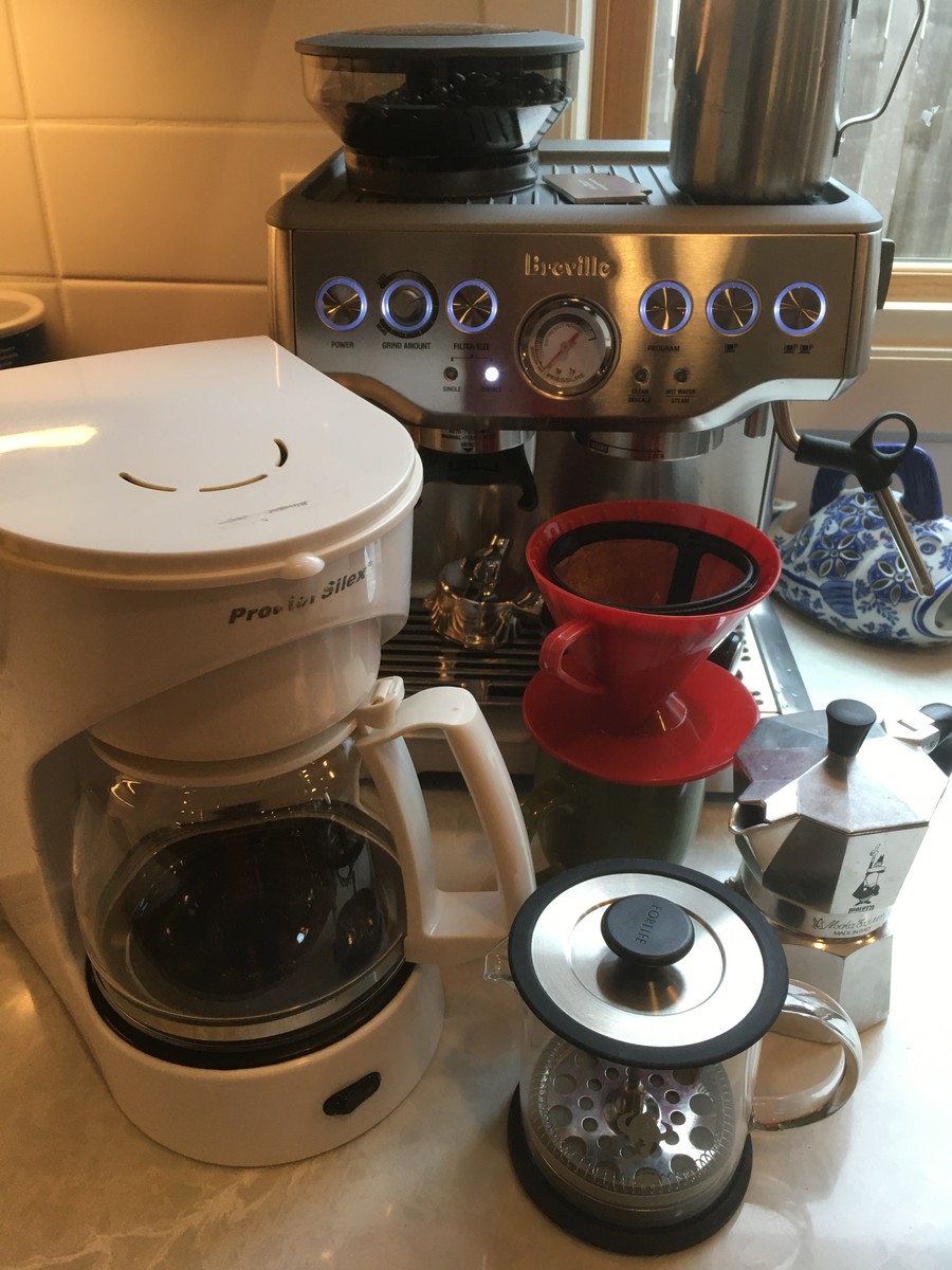 A collection of coffee makers on a kitchen counter: cheap electric auto drip coffee maker; small French Press; stovetop Bialetti espresso machina; simple pour-over cone; large and fancy Breville espresso machine & steamer with a built-in grinder