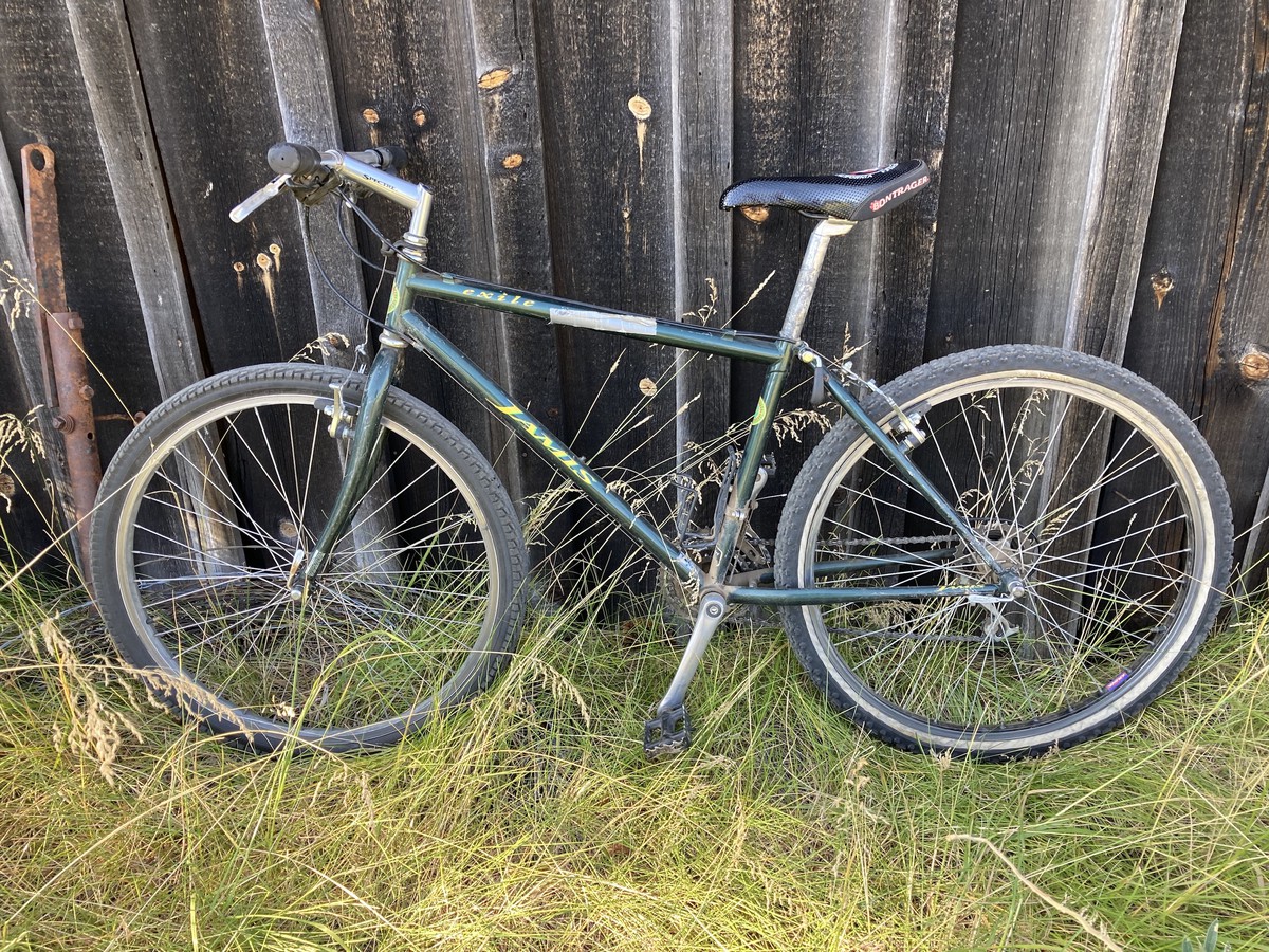 Well-loved and worn Jamis Exile mountain bike, leaning against a weatherworn wooden barn wall