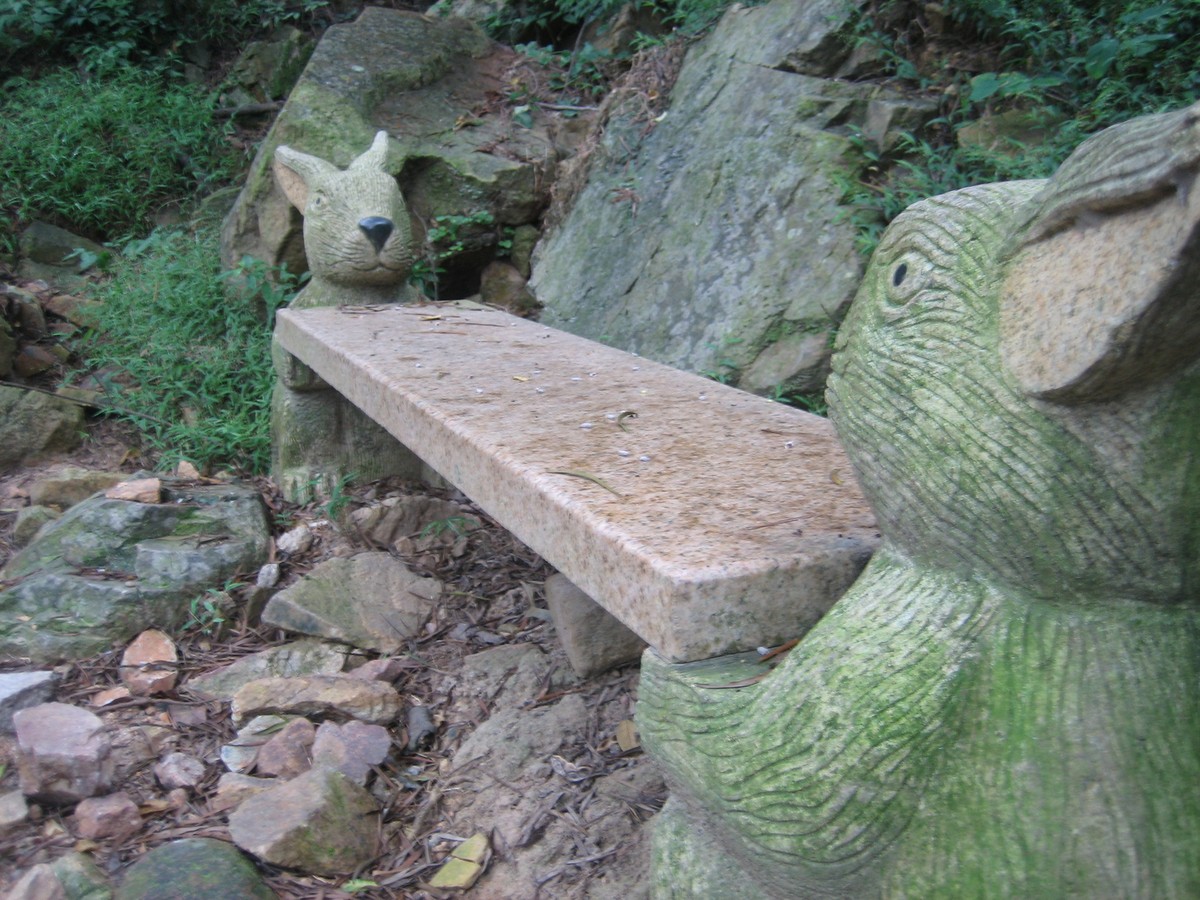 Closeup of rabbit statues holding a stone bench