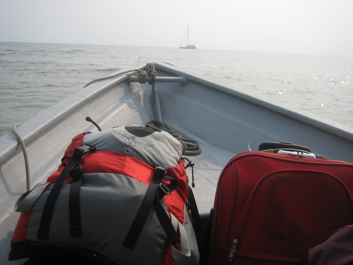 Two backpacks in the bow of a small boat on a broad, calm, tropical sea