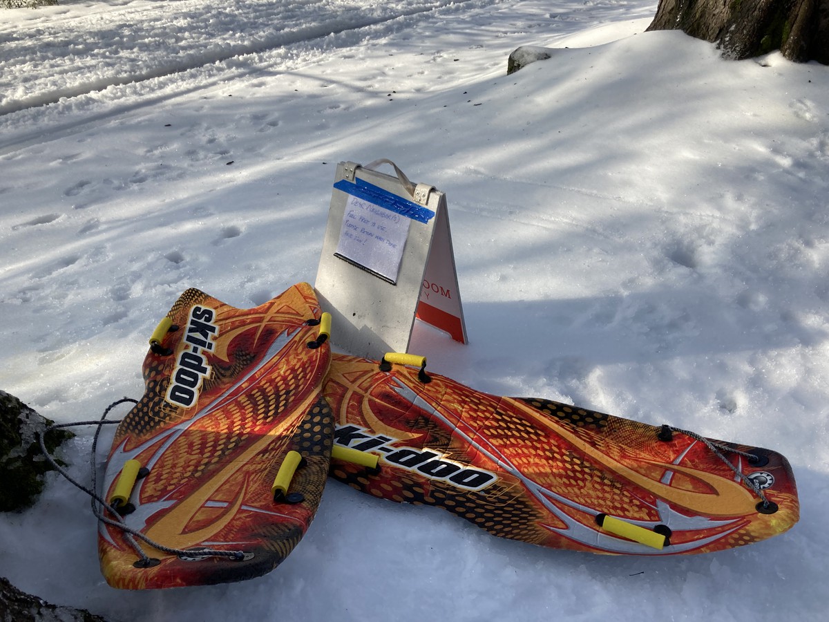 Neighborhood ski/sleds. Sign reads “Dear neighbor(s) Feel free to use. Please return when done. Have fun!”