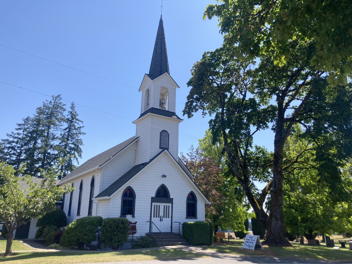 A trim white rural church dating to probably the early 20th century, next to a well-kept cemetery