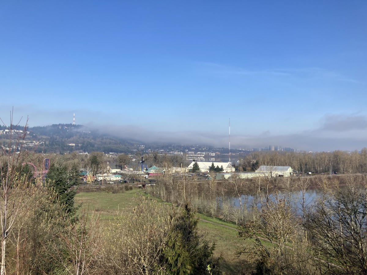 View from Sellwood Park, across Oaks Bottom and Oaks Park, toward the Stonehenge Tower on Council Crest. The morning clouds are burning away, wisps of mist cling to the hillside