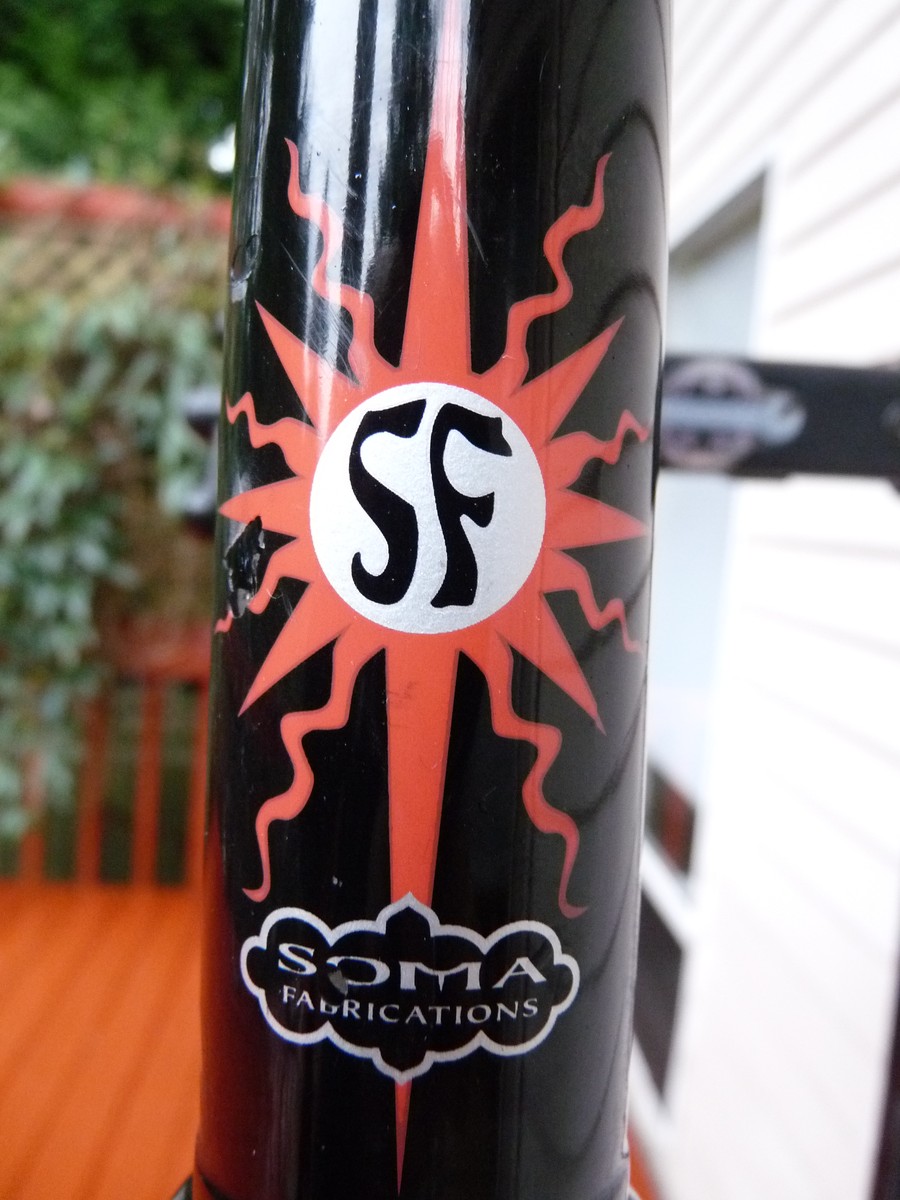 Closeup of head badge on a Soma Doublecross bicycle: Logo is a stylized “SF” in a sunburst, with “SOMA Fabrications” just below it