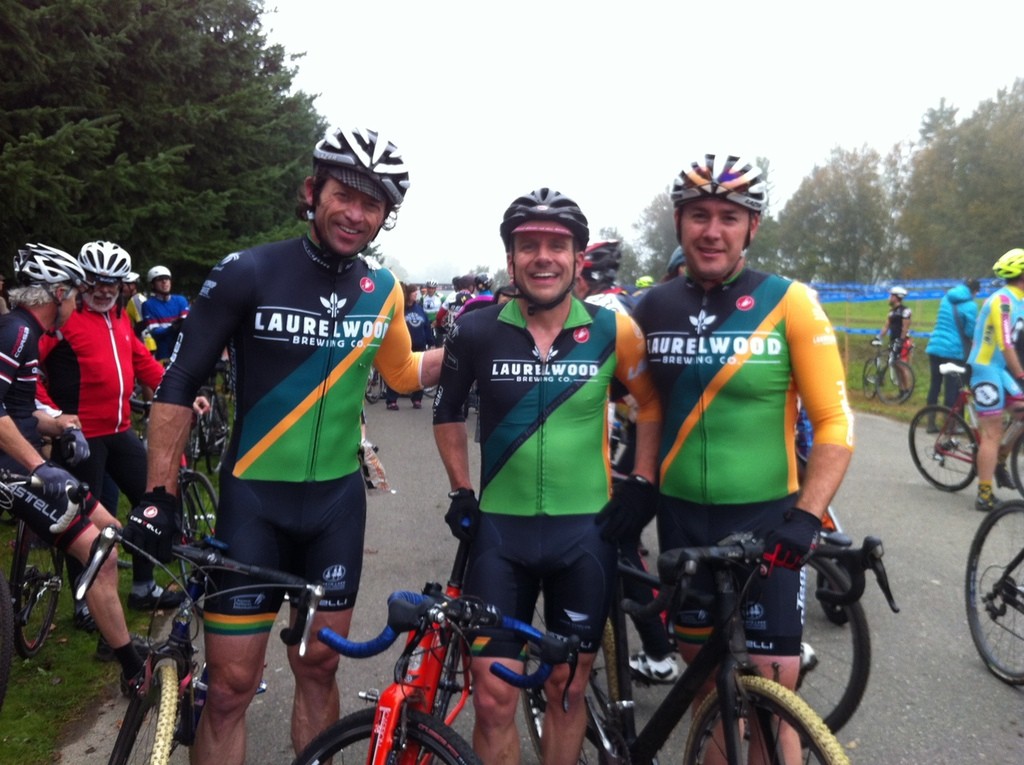 Three middle-aged men in Laurelwood/Team Oregon racing skinsuits, at a cyclocross bicycle race