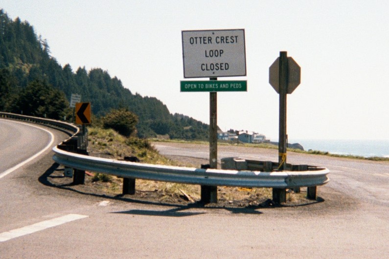 Sign on a mountainous coastal road, reads: Otter Crest Loop CLOSED (open to bikes and peds)