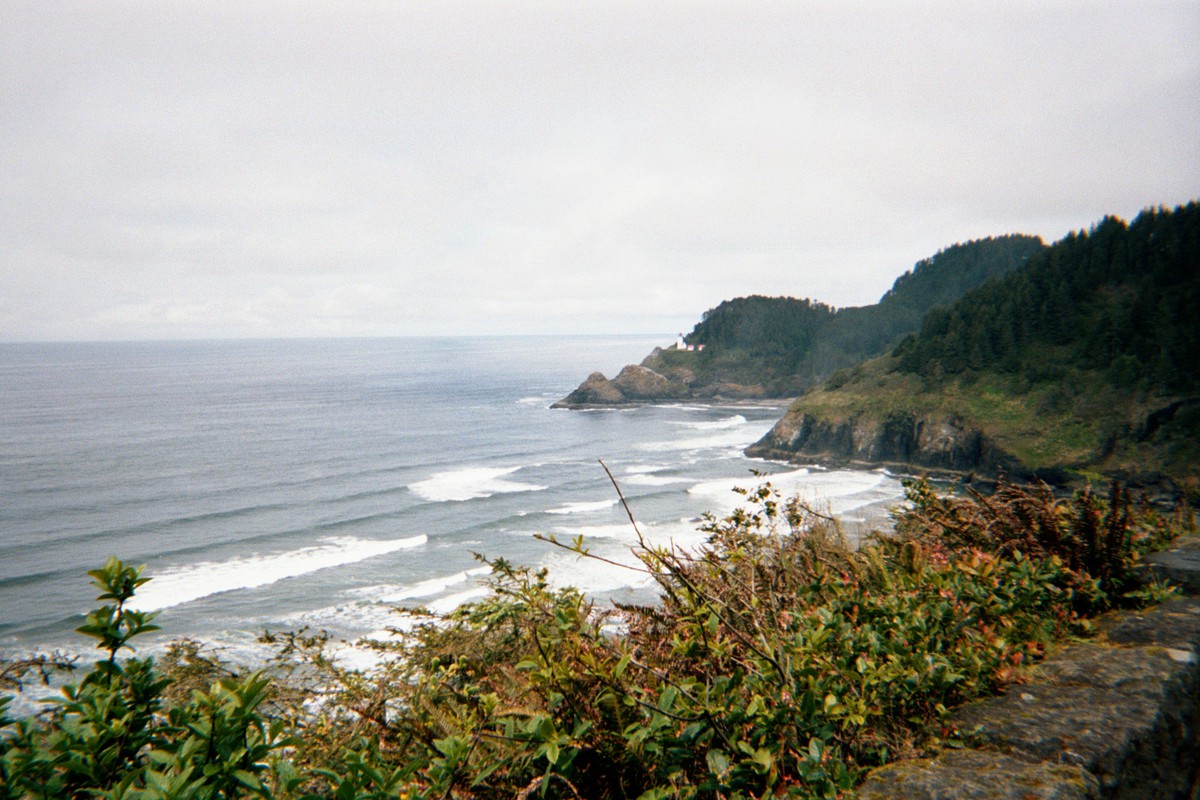 Landscape taken from a headland about 300' above the Pacific Ocean north toward another headland a few miles distant, with a lighthouse (Heceta Head)
