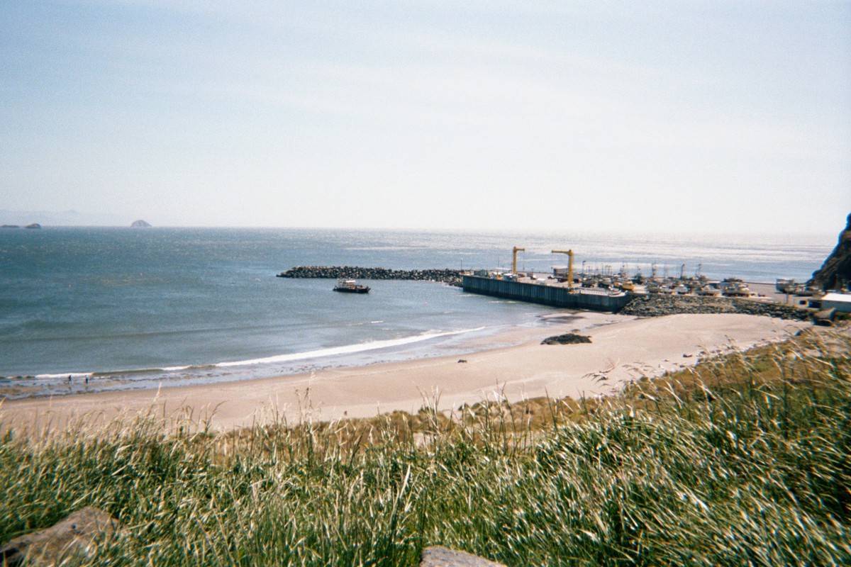 Jetty and dock with a complex gantry designed to lift boats from the water, next to a broad beach. Weather clear and windy