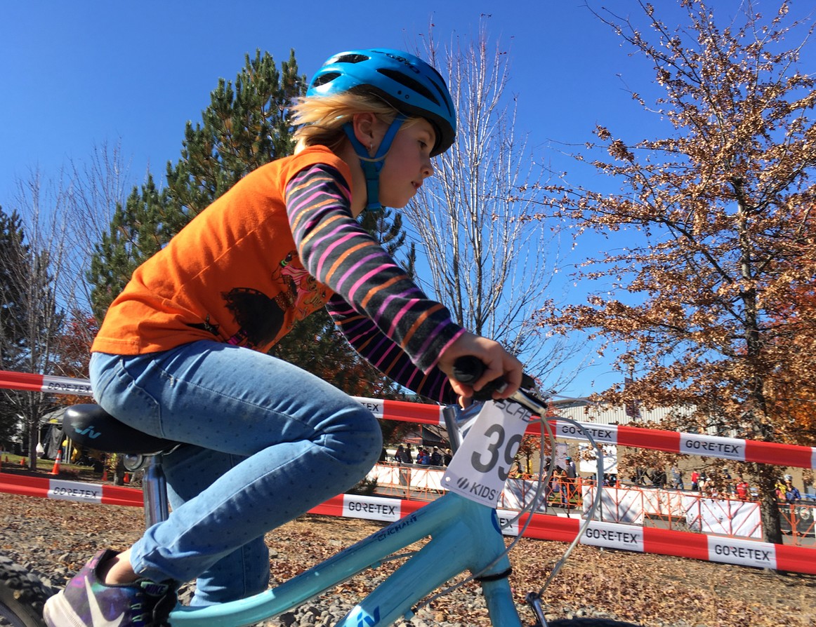 School age girl on a bicycle with a race number, on a cold sunny day