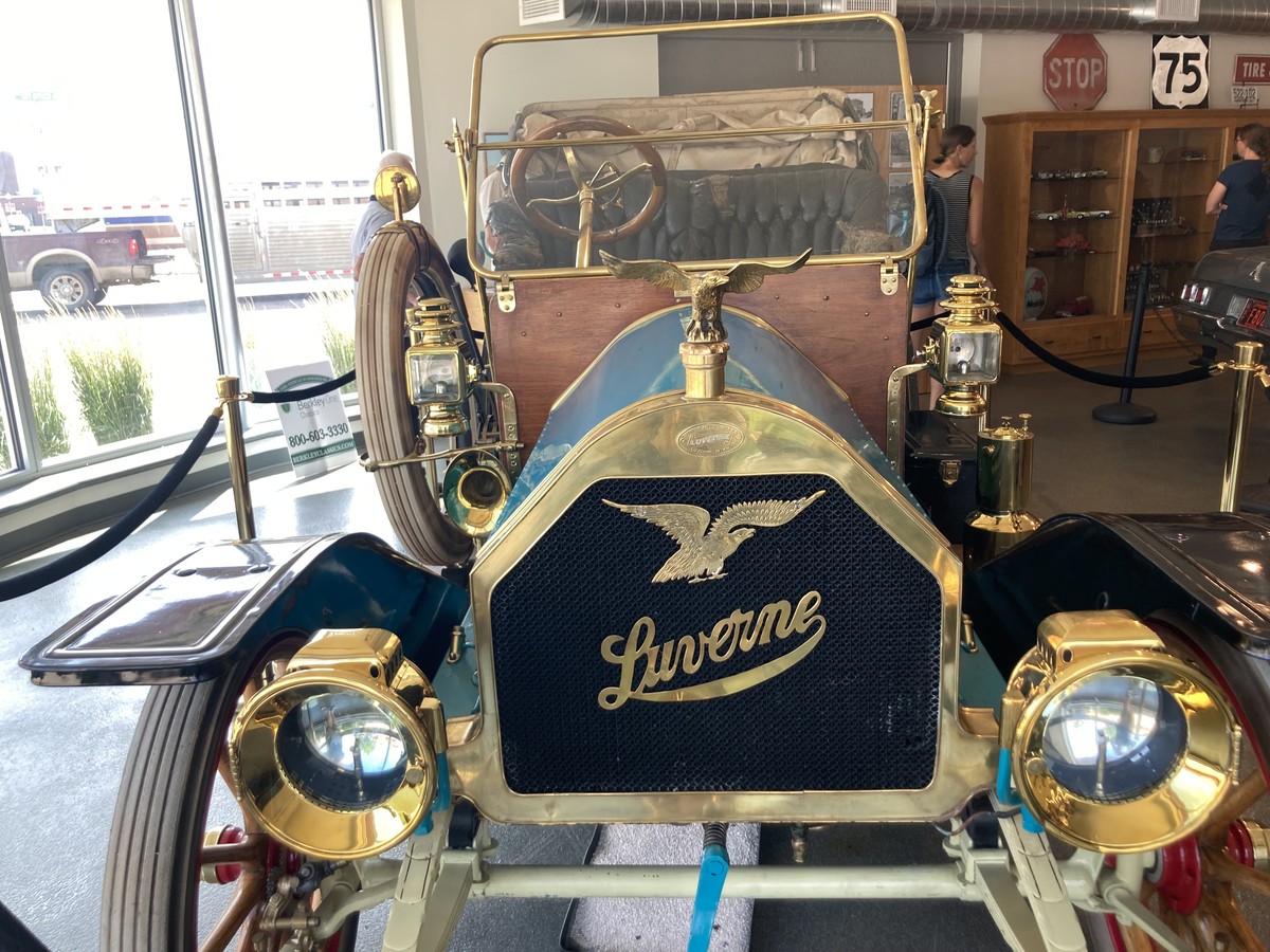 Front of a fancy 1906 open-top car, with brass fittings and accents; on the grille: an eagle logo and “Luverne” in graceful script