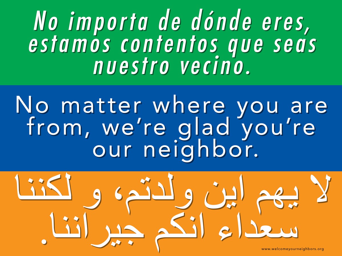 Text from a sign, reads “No matter where you’re from, we’re glad you’re our neighbor” with translations into Spanish and a language written with Arabic script (presumably Arabic)