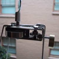 Closeup of a spindly windup toy of uncertain purpose, on a windowsill looking into the courtyard of an apartment building
