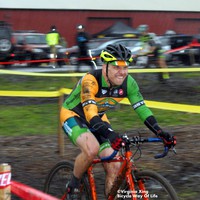 middle aged man racing in cyclocross skinsuit, biting his lower lip, covered in mud, in the driving rain, motion blur. Credit: ©Virginia Xing, Bicycle Way of Life