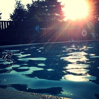 low perspective photo of a small swimming pool with no one in it, taken at sunset on the last day of summer
