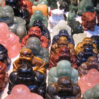 Closeup of several small Buddha figurines (and one owl, and one rabbit) carved in various minerals like jade and soapstone, for sale in a Hong Kong street market
