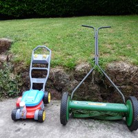 Plastic toy lawnmower and a reel or “push” mower, side by side