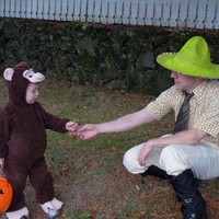 A toddler in a monkey costume and a man in a yellow hat, for Halloween