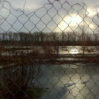 Ruins of Tequila Willies at sunrise on a rainy day, shot through a chainlink fence