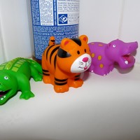 Closeup of three animal squirty bath toys and a bottle of Dr. Bronner’s soap, on the ledge of a bathtub