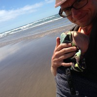 Selfie on a beach with Ada, asleep in the Ergo carrier