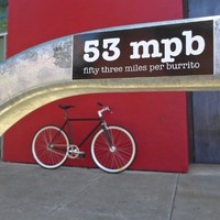 Sticker on a bike rack reading “53 miles per burrito”