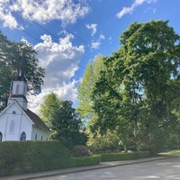 Oaks Pioneer Church on a sunny May day, with the US flag hanging limply in front of it