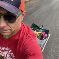 Selfie taken while riding the cargo bike, downward view, my face only partially visible, several bags of groceries on the bike behind me