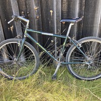 Well-loved and worn Jamis Exile mountain bike, leaning against a weatherworn wooden barn wall