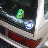 Closeup of two decals on the right rear of a 1990 honda civic. One is an “Oregon duck” sticker; the other is of Antarctica