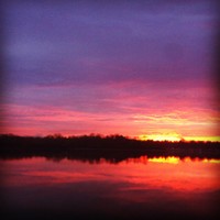 Heavily filtered riverscape, orange sky and rising sun reflected in the Willamette river