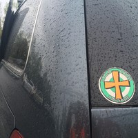 Closeup of a “Cyclocross Crusade” sticker on the window of a minivan, wet with rain