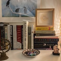 Several stacks of books and knickknacks on top of a shelf
