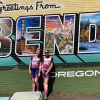Two VALKYR juniors in front of a mural reading Greetings from BEND Oregon