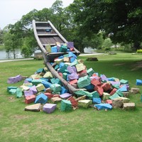 Public artwork from Xiamen, Fujian: an old-style flatbottom boat on a grassy lawn, filled with blocks of stone painted bright colors; the boat appears to be capsizing and tipping these blocks onto the lawn