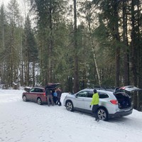 Two Subarus parked on a snowy road in the forest