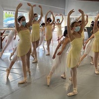 Young ballet dancers practicing in studio, wearing N95 masks & tutus