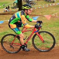 Middle aged man in Team Oregon skinsuit on a cyclocross racing bike, face contorted with visible effort