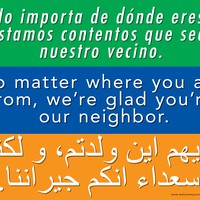 Text from a sign, reads “No matter where you’re from, we’re glad you’re our neighbor” with translations into Spanish and a language written with Arabic script (presumably Arabic)